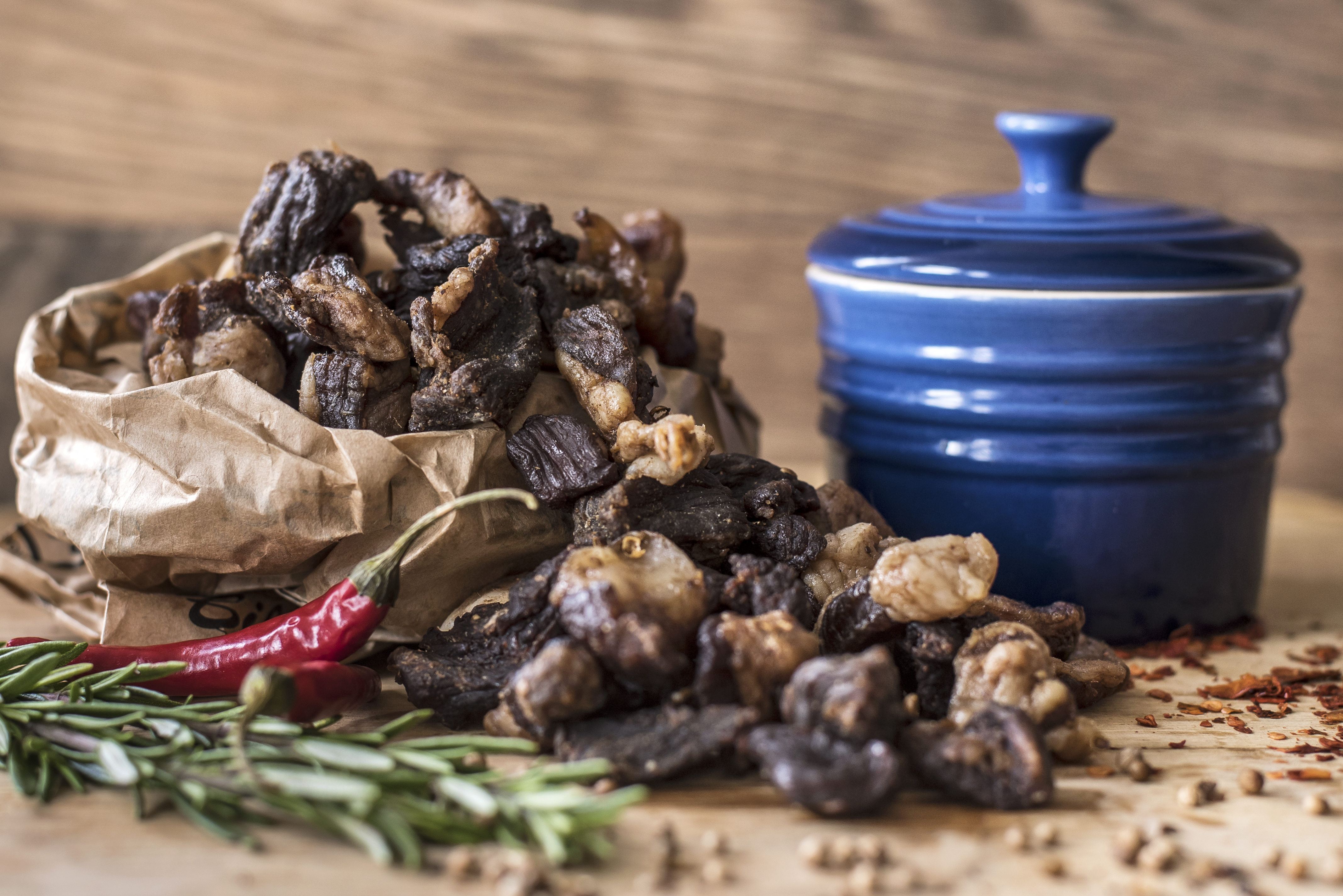 Biltong pieces with a side of fat sitting on a table with herbs